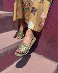 Person wearing green sandals on a maroon step with an embroidered mustard yellow skirt.